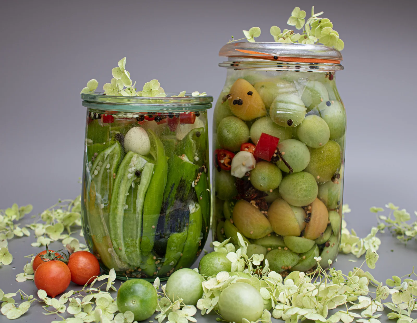 Preserved vegetables in glass jars on a muted grey surface